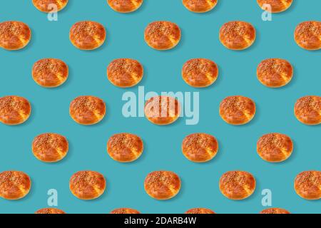 A loaf of white bread sprinkled with sesame seeds on a turquoise isolated background. Seamless pattern. Original packaging design Stock Photo