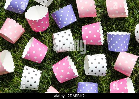 Multi-colored empty polka dot paper molds of white, purple and pink colors for cupcakes on green grass. Stock Photo