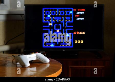 KHARKOV, UKRAINE - NOVEMBER 12, 2020: Dendy video game controller on table with Pac Man game on big display Stock Photo