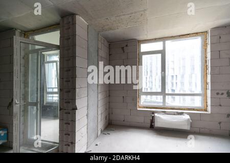 Small apartment without repair in a new building. A room in an unfinished house. Walls of foam block and concrete floor in a tiny apartment. Stock Photo