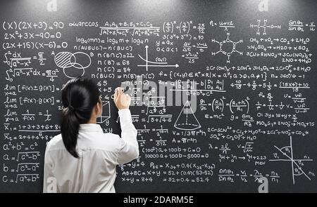 Rear view female teacher write on blackboard Stock Photo