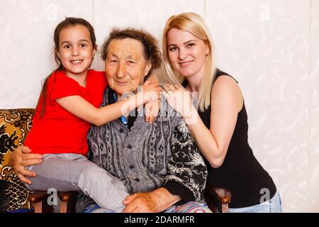 Senior woman hugging granddaughter while sitting on sofa at home Stock Photo