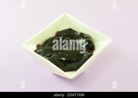 Black currant jelly preserves in white condiment bowl on lavender background Stock Photo