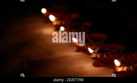 Indian traditional clay lamps with glowing flames kept together in a row during celebrations of indian hindu cultural festival of diwali or kali puja. Stock Photo