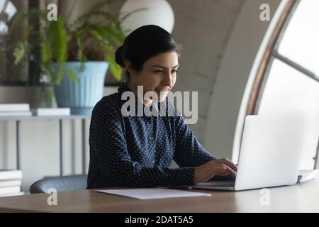 Confident Indian businesswoman working on laptop in modern office Stock Photo
