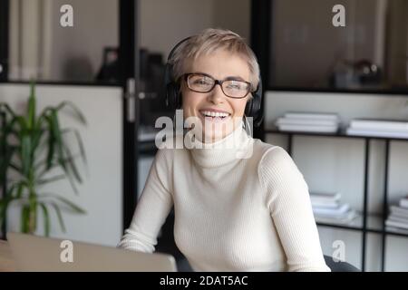 Close up smiling businesswoman wearing headphones looking to aside Stock Photo