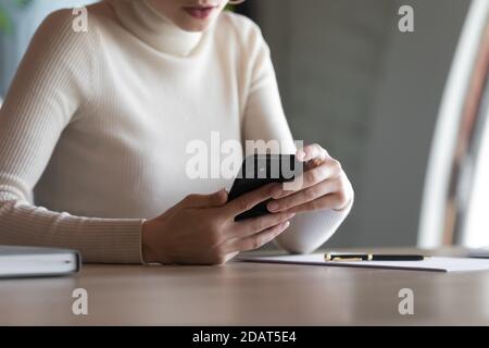 Close up businesswoman using smartphone, sitting at work desk Stock Photo