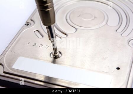 Opening of hard disk for data recovery Isolated on white background. Dismantled hard drive. Screwdrivers for computer repair. Stock Photo