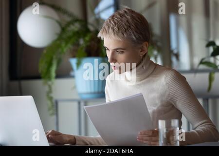 Focused businesswoman working with documents, using laptop in office Stock Photo