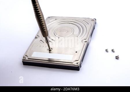 Opening of hard disk for data recovery Isolated on white background. Dismantled hard drive. Screwdrivers for computer repair. Stock Photo