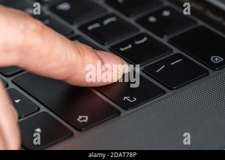 close-up female hand pressing enter button on a laptop keyboard Stock Photo