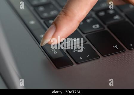 close-up female hand pressing esc button on a laptop keyboard Stock Photo