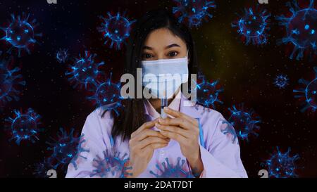 female doctor holding syring of virus vaccine and coronavirus (covid-19) floating in the air Stock Photo