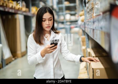 woman worker using smartphone to checking inventory in the warehouse store Stock Photo