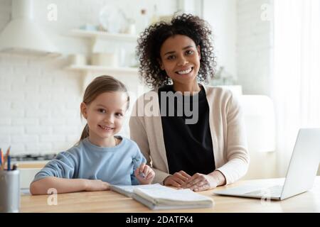 Head shot portrait smiling African American mother with daughter studying Stock Photo