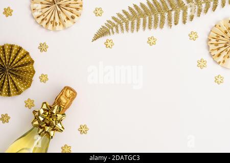 Festive white background with gold decoration , bottle of sparkling wine and christmas decorations, glittering snowflakes and shiny golden fern leaves Stock Photo