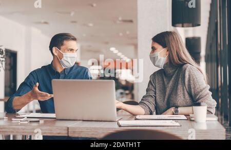 business colleagues in protective masks sitting at the office Desk. Stock Photo