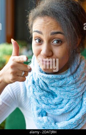 Portrait of an African American woman making a video call. She points her finger at you. Close-up picture. Stock Photo