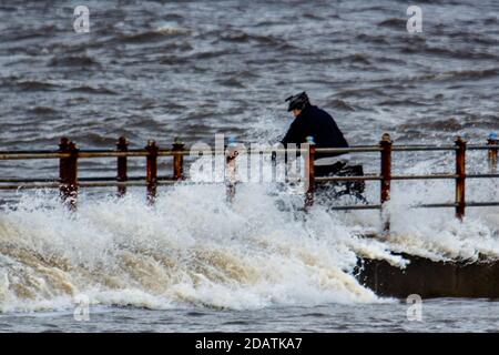 Heysham Lancashire, United Kingdom. 15th Nov, 2020. Cyclyist caught in Eaves trying to photograph waves on the Grosvenor Breakwater Credit: PN News/Alamy Live News Stock Photo