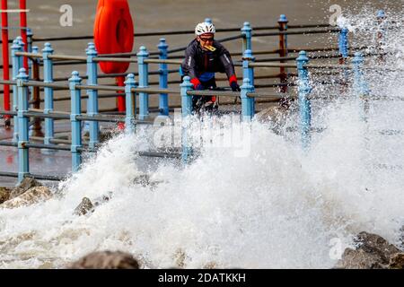 Heysham Lancashire, United Kingdom. 15th Nov, 2020. Cyclyist caught in Eaves trying to photograph waves on the Grosvenor Breakwater Credit: PN News/Alamy Live News Stock Photo