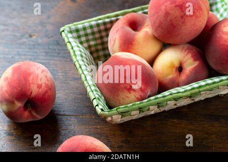 Fresh, ripe peaches in a basket on a wooden table. Delicious and healthy fruits. Healthy food concept. Stock Photo