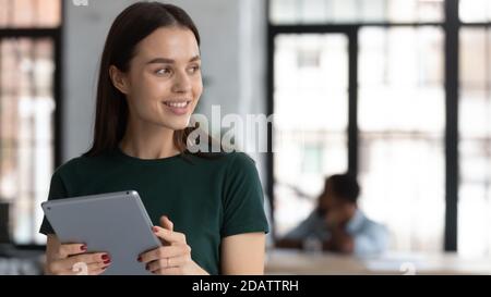 Smiling young woman looking aside while working at digital pad Stock Photo
