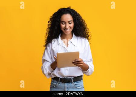 Smiling Young Brunette Woman Using Digital Tablet, Browsing Social Networks Stock Photo