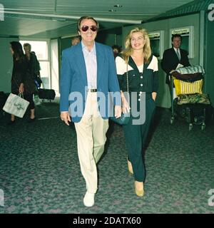 Des O'Connor with his wife Jodie Brooke Wilson at London Heathrow Airport 1992 Stock Photo