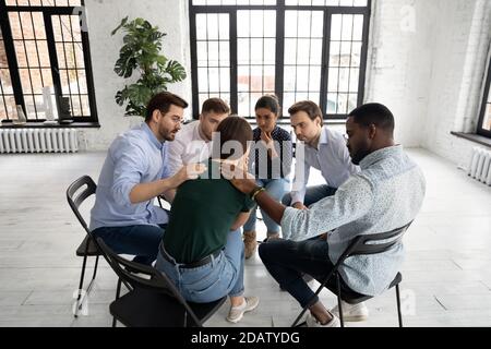 Professional psychologist and supportive diverse group mates comforting stressed woman Stock Photo