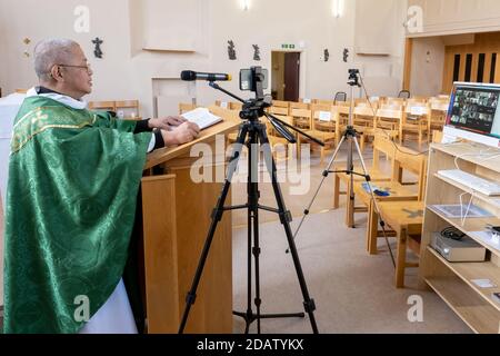 A priest preaches to an empty church during lockdown, the congregation is following on Zoom and Facebook Stock Photo