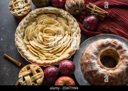 Dessert tarts on a table. Top view photo of various apple pies, cakes and tarts, fresh plums, apples and pumpkins. Autumn menu ideas. Stock Photo