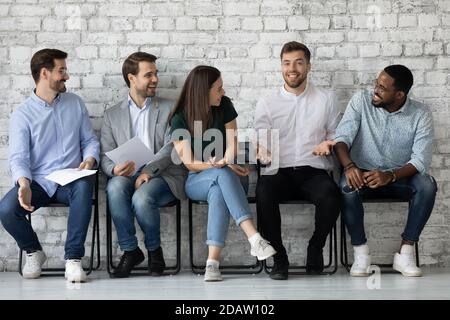 Diverse laughing young people waiting for exam enjoying cute jokes Stock Photo