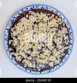 Cocoa and coconut cake covered with chocolate glaze and almond flakes, on a white background Stock Photo