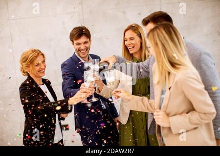 Group of excited business people celebrating and toasting with confetti falling in the office Stock Photo