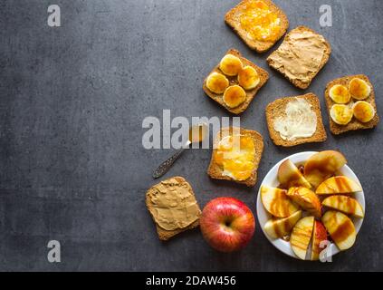 Frame or border made of toast bread with different toppings. Sweet breakfast top view photo. Dark grey textured background with copy space. Stock Photo
