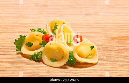 Orecchiette pasta, with turnip tops and chilli, on a wooden base. Stock Photo