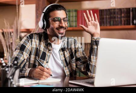 Arab Student Guy At Laptop Waving Hello Learning At Home Stock Photo