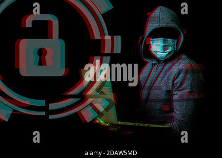 Man in a mask without a face and a hood holds a laptop in his hands on a dark background. Concept of cyber rogue, hacker. Banner. Added glitch effect. Stock Photo