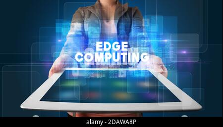 Young business person working on tablet and shows the inscription: EDGE COMPUTING Stock Photo