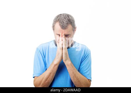 Depressed middle aged man praying over white background.  Middle aged man praying for help with a desperate look over white background. Stock Photo