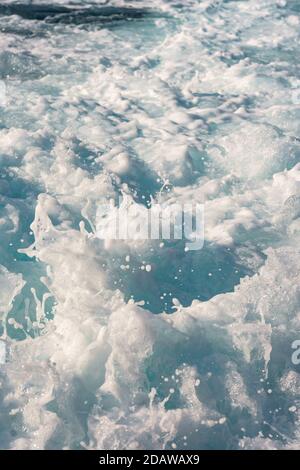 Water surface background. Blue sea water splashes with sun reflections. Ripples of water in the.