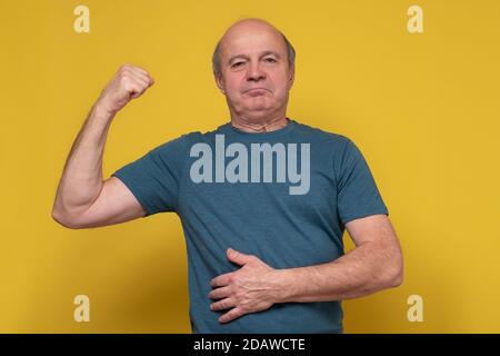 Senior man showing arms muscles smiling proud. Stock Photo