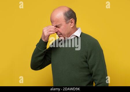 Mature man touching his nose with hand, with closed eyes, trying to concentrate Stock Photo