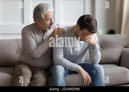 Caring loving mature father calming hugging upset adult son Stock Photo