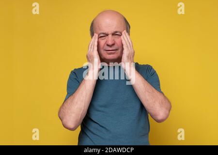 Man touching his temples with hand, with closed eyes, trying to concentrate Stock Photo