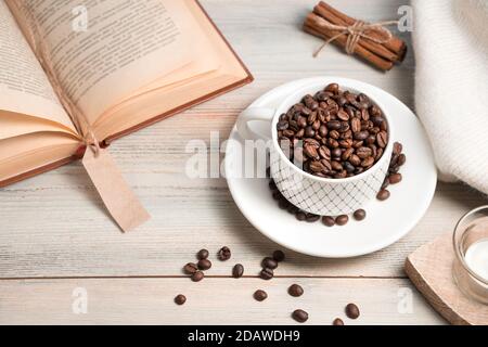 Coffee background with grains poured into a Cup and a book on a light background. Stock Photo