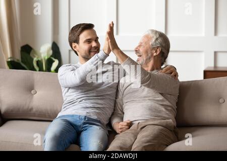 Overjoyed mature father and adult son giving high five Stock Photo