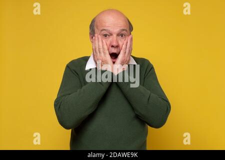 Surprised caucasian man with glasses holding hands near face. Stock Photo