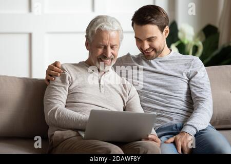 Happy senior father with son using laptop at home together Stock Photo
