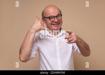 Mature man making call me gesture, sign with hand shaped like phone. Stock Photo